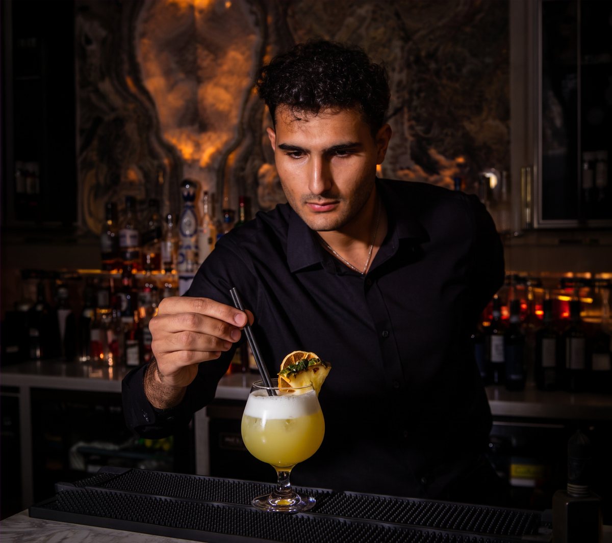 Un barman completa un cocktail al bancone di Amami Italia