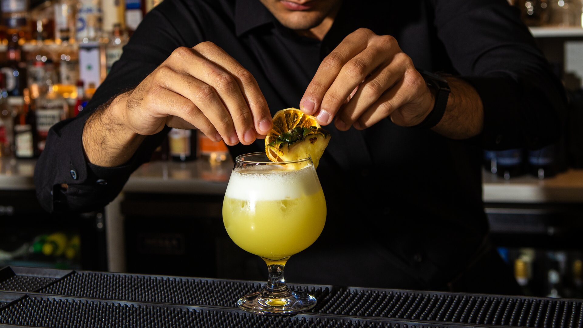 Un barman rifinisce un cocktail giallo con una rondella di limone al bancone di Amami Italia, a Brampton