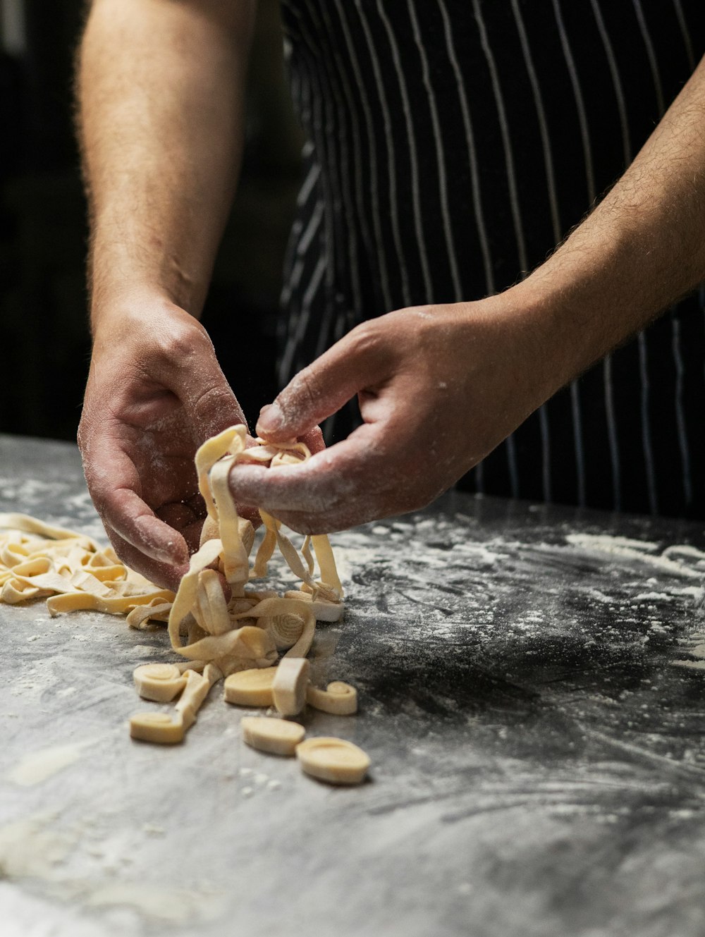 Mani che modellano la pasta fresca su un tagliere infarinato