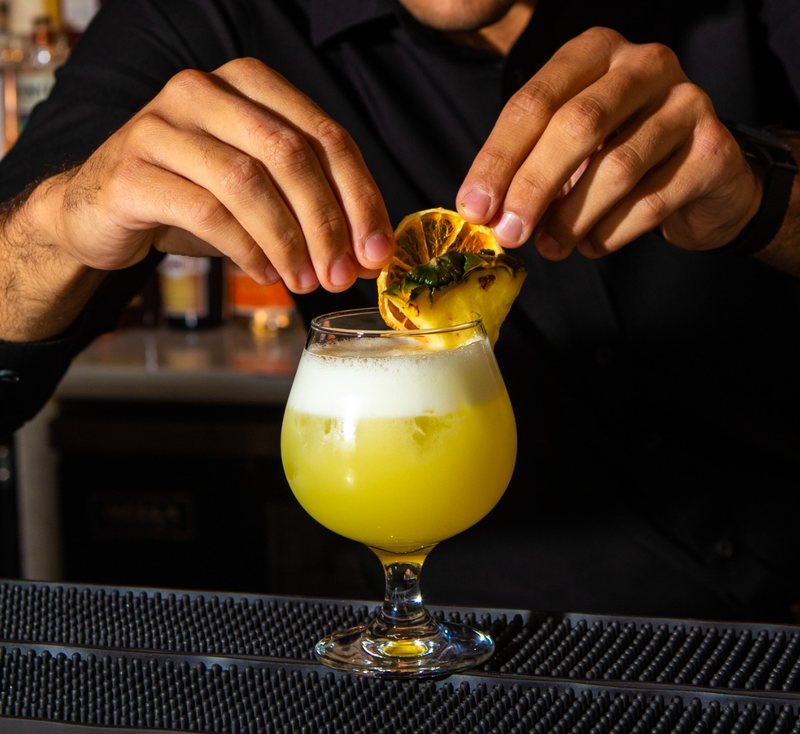 Un barman completa un cocktail giallo con una rondella di limone