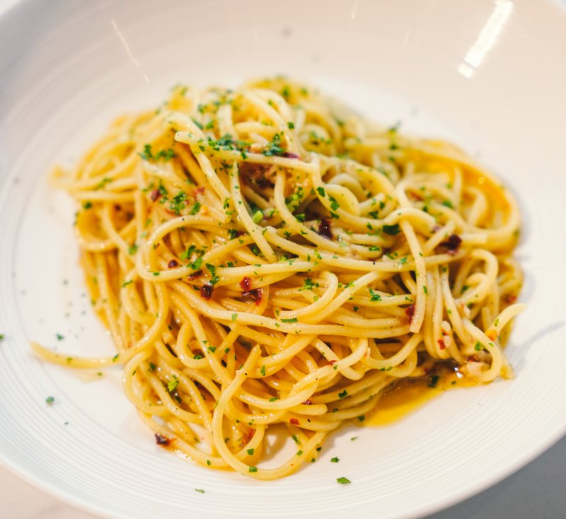 Spaghetti aglio e olio in un piatto bianco