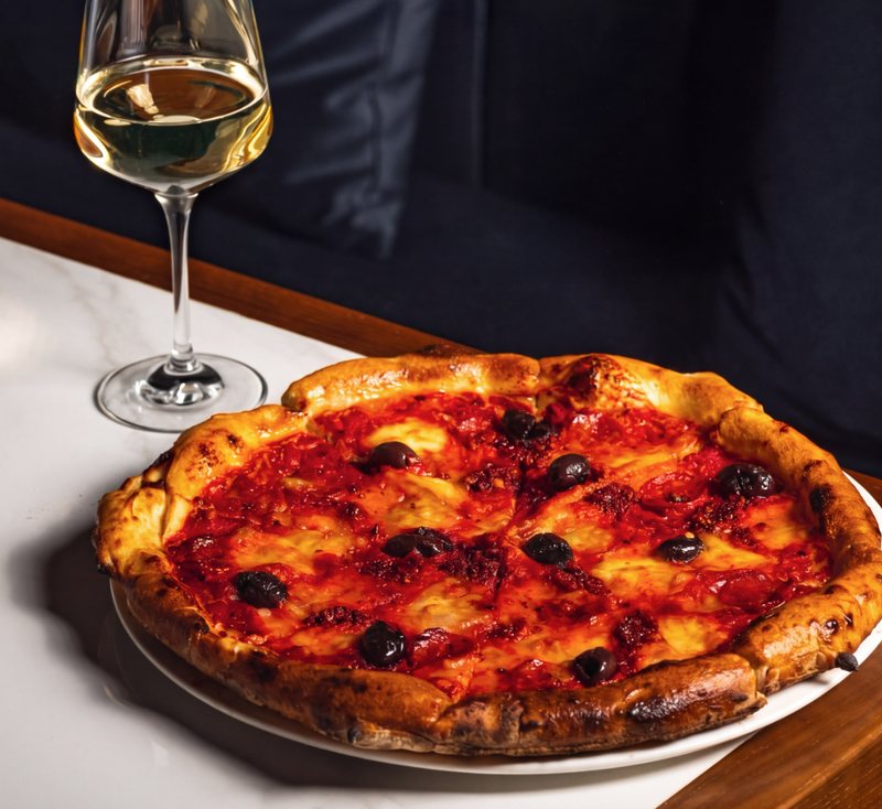 Una pizza napoletana con un calice di bianco
