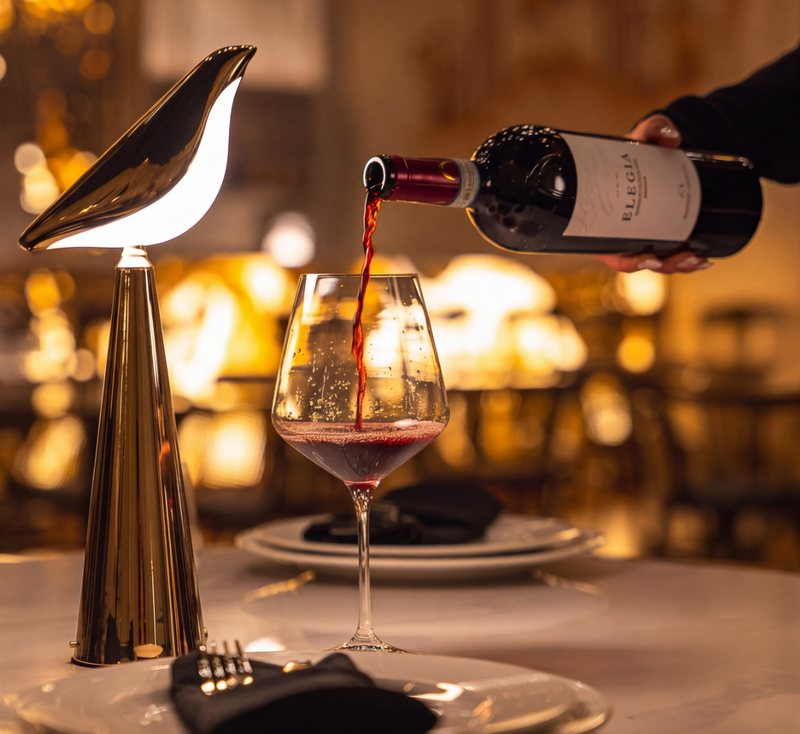 Vino rosso versato a un tavolo a lume di candela